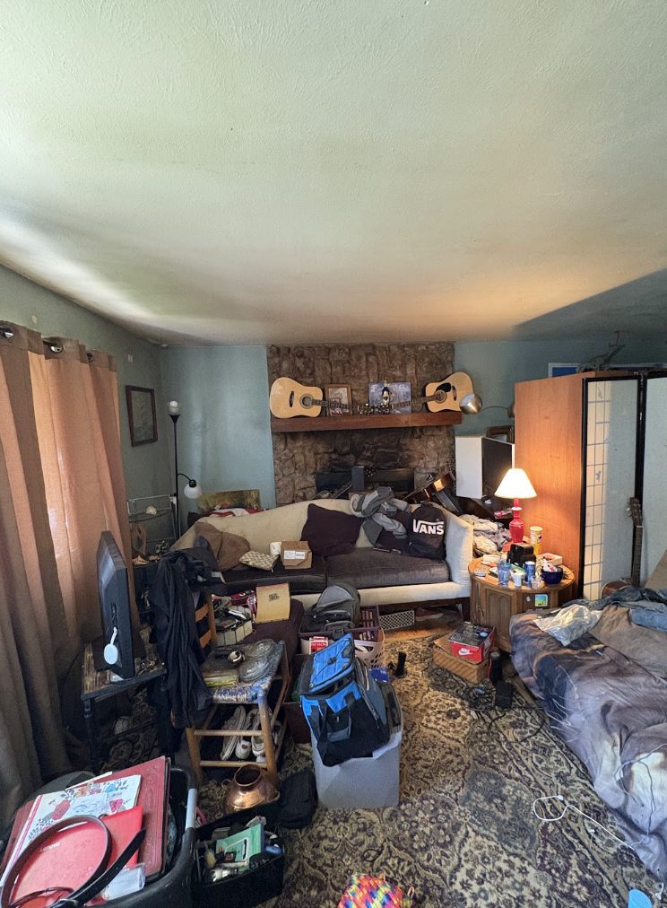 Cluttered living room with a dated stone fireplace before renovation, Lakewood 80232