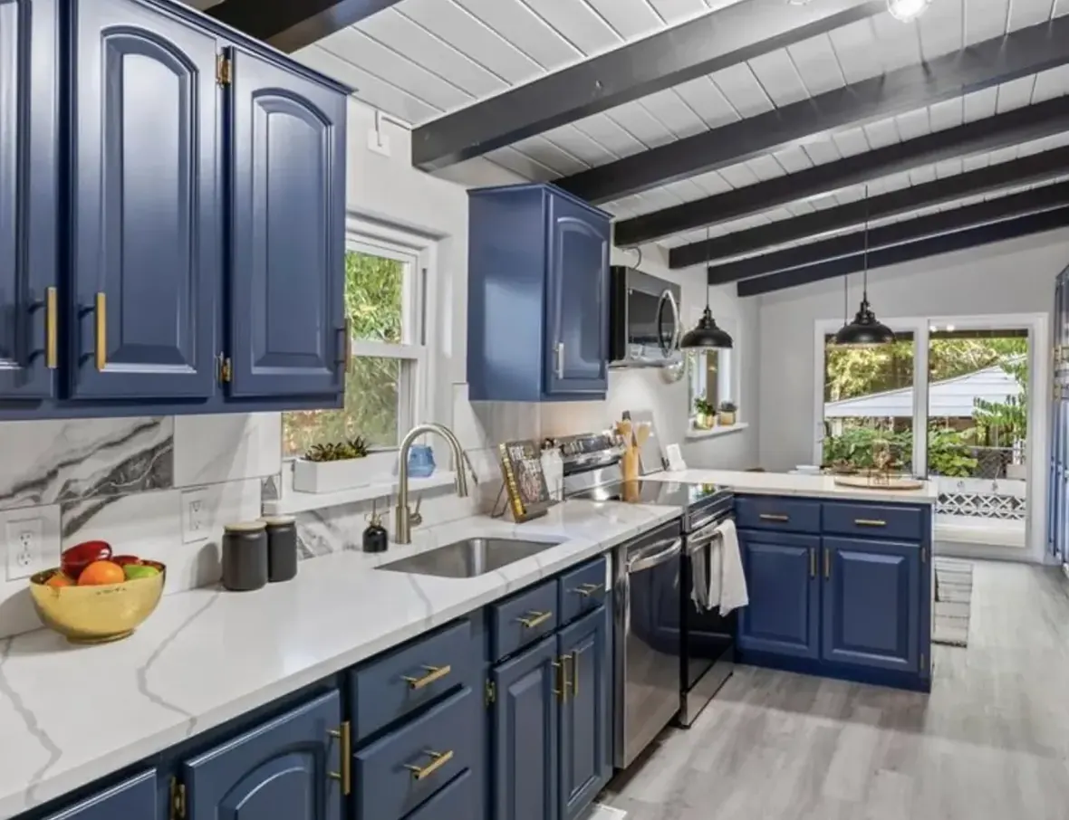 The same kitchen with navy cabinets, marble counters and the original beams blackened, Westminster Colorado